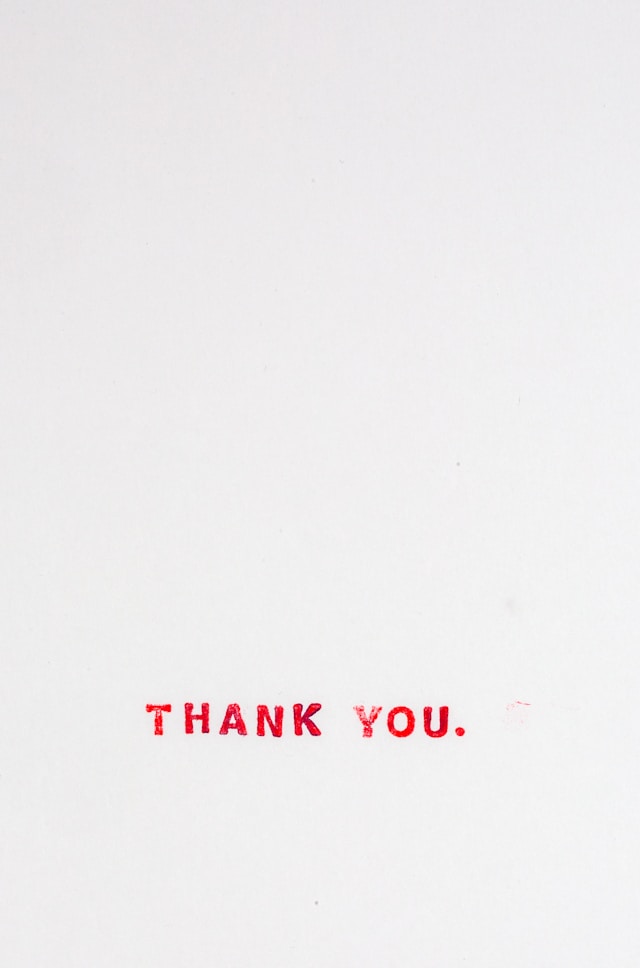 texto en rojo sobre papel que dice "gracias" en ingles. Thank you